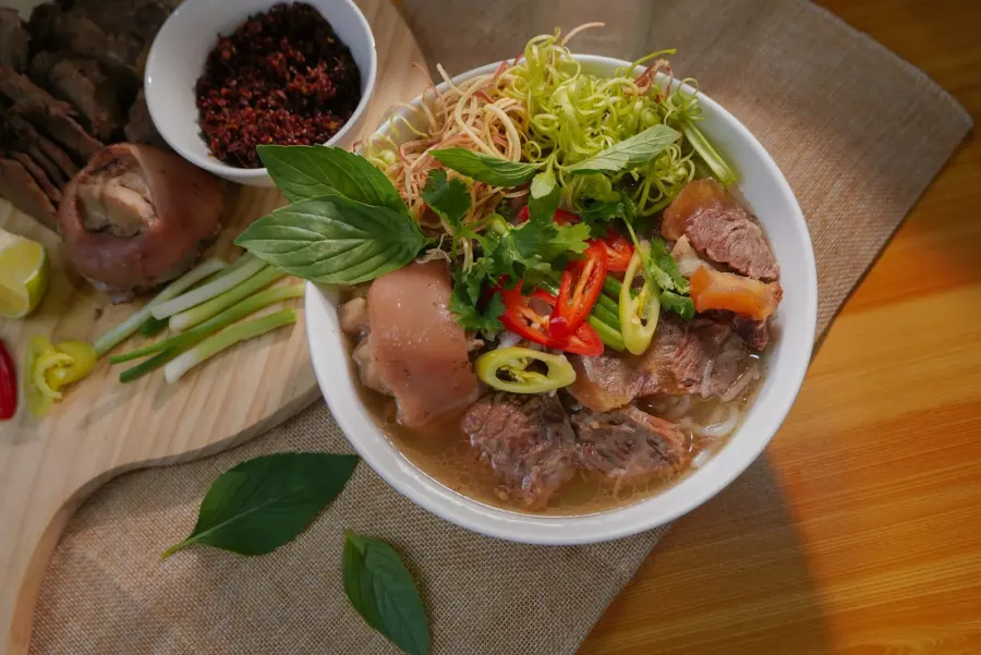 A white ceramic bowl of soup with fresh greens