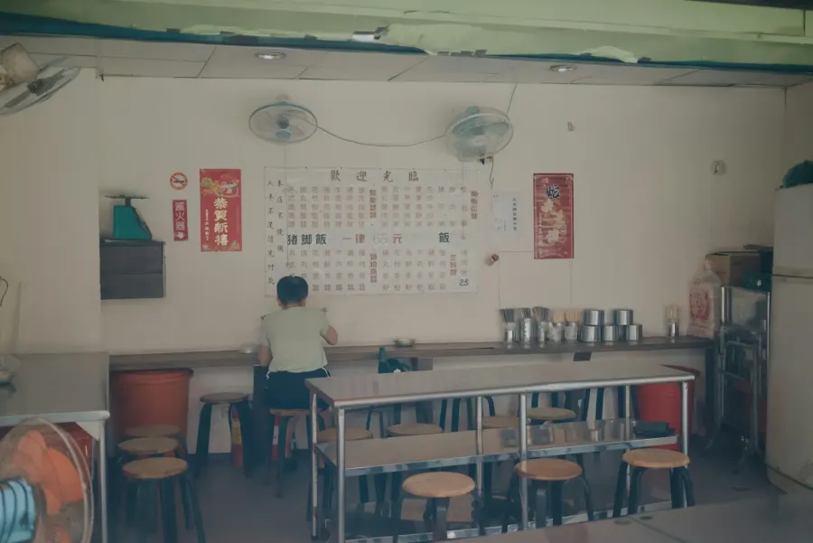 A person seated at a table in a small restaurant
